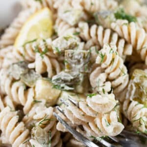 Dill pickle pasta salad in white bowl with fork.