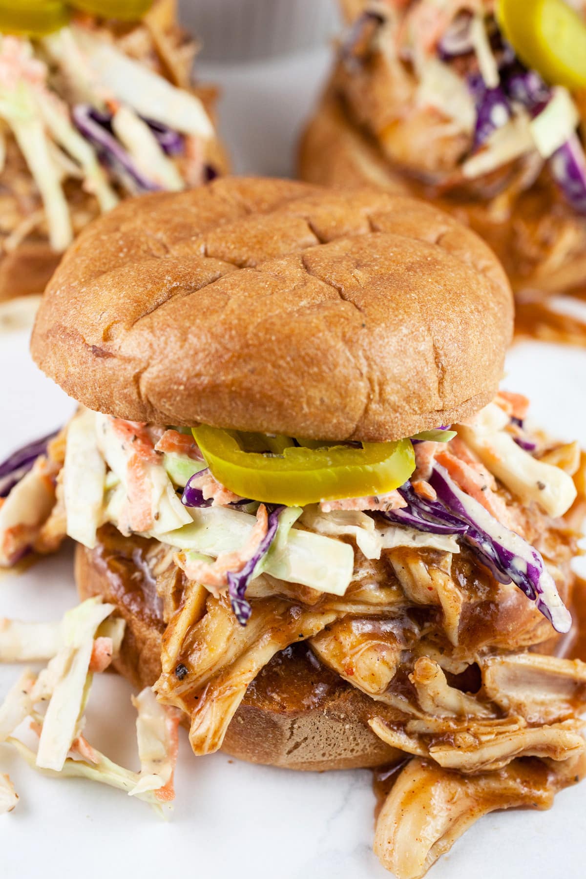 Pulled BBQ chicken sandwiches with coleslaw and pickled jalapenos on toasted buns.