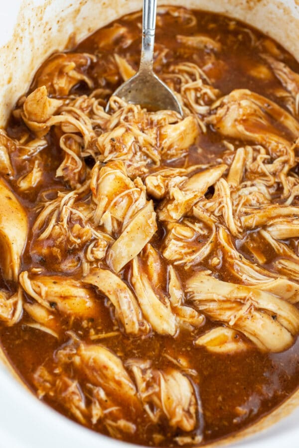 Cooked shredded chicken tossed in BBQ sauce in crockpot.