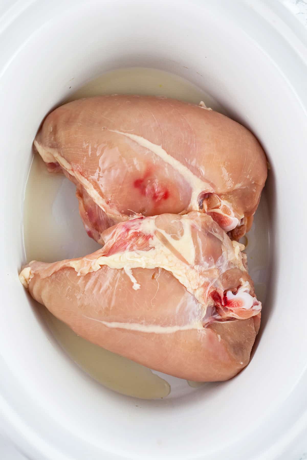 Raw split chicken breasts in slow cooker.