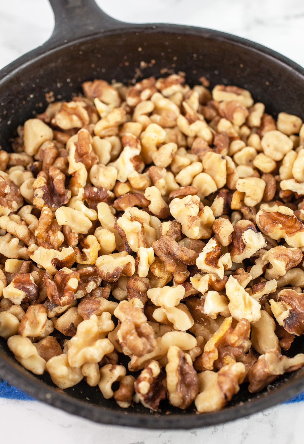 Toasted chopped walnuts in cast iron skillet.
