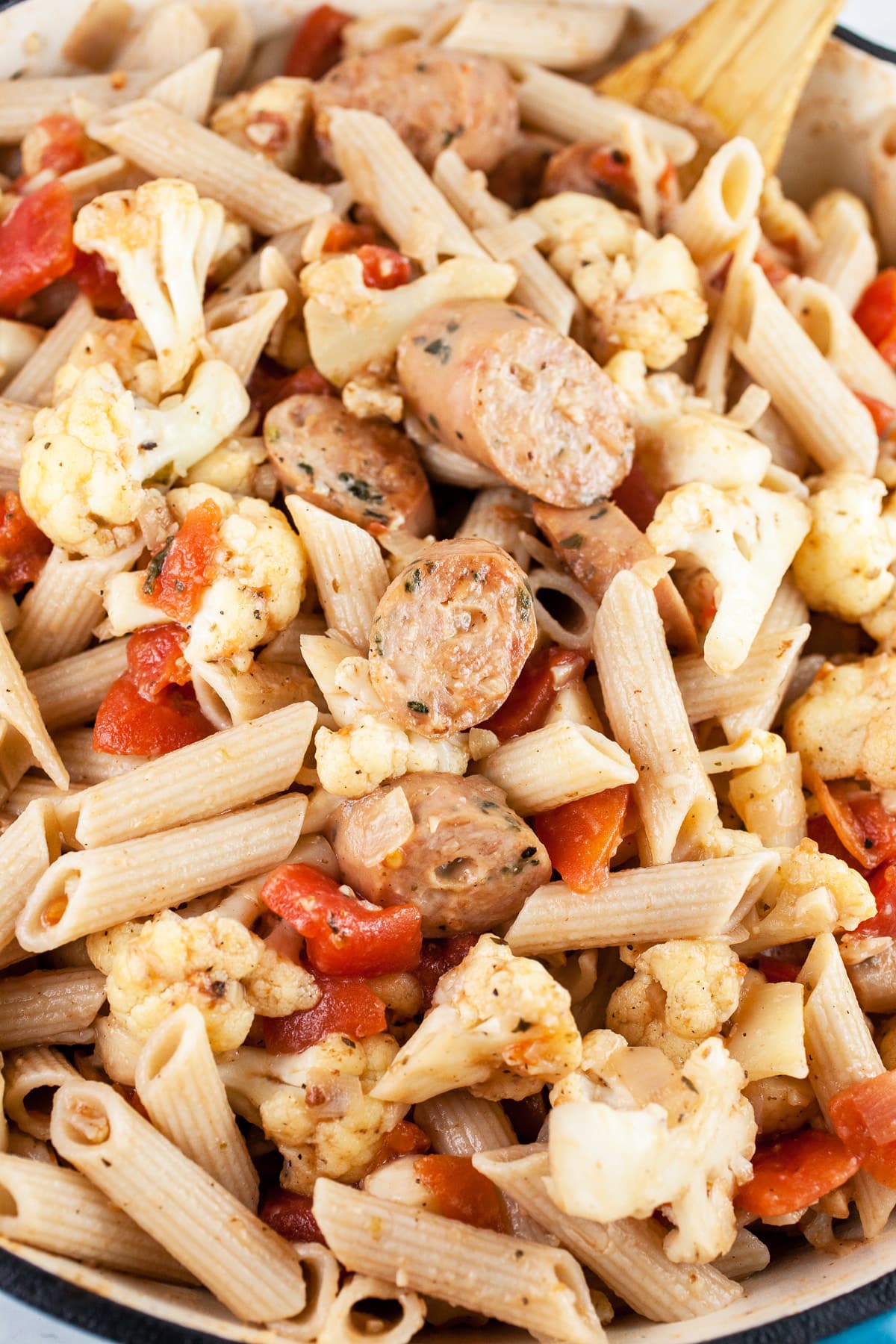 Cauliflower, tomato, and sausage penne pasta in skillet.