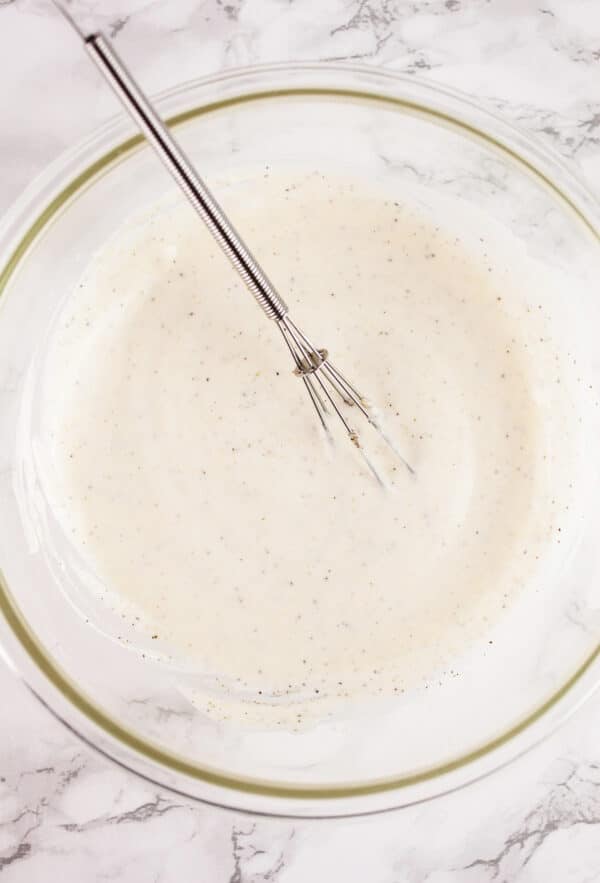 Mayo and lemon juice combined in glass bowl with whisk.