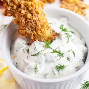 Walleye finger dipped into small bowl of dill tartar sauce.