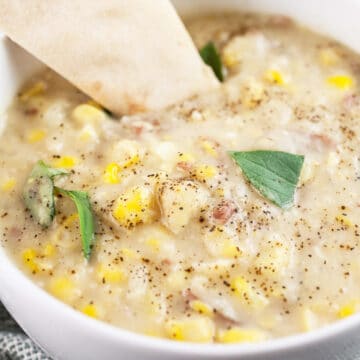 Thai potato corn chowder with slice of flatbread in white bowl.