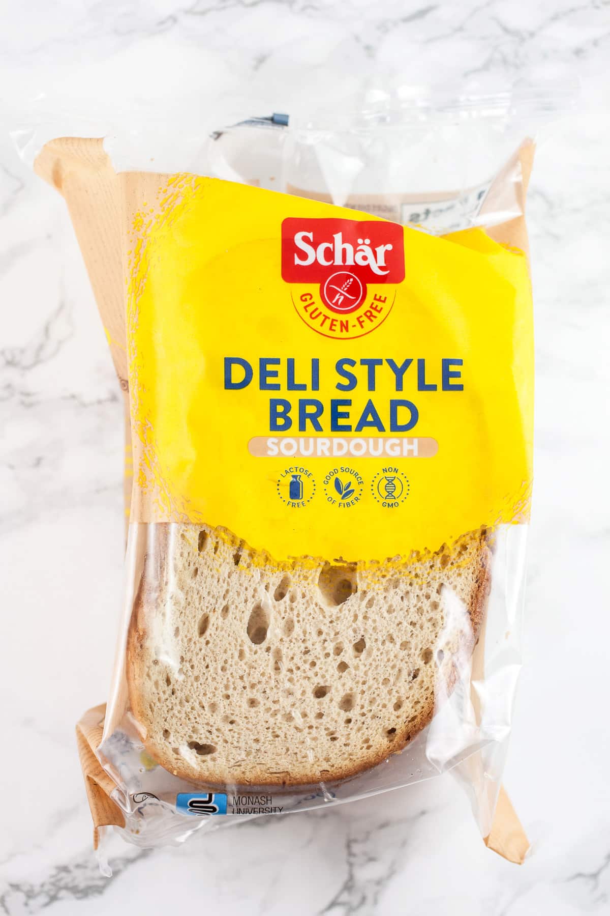 Unopened package of gluten free deli style bread on white surface.