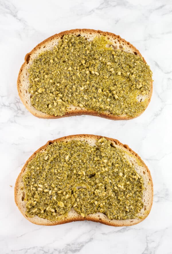 Basil pesto spread onto two slices of bread.