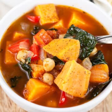 Sweet potato kale soup in white bowl with spoon.