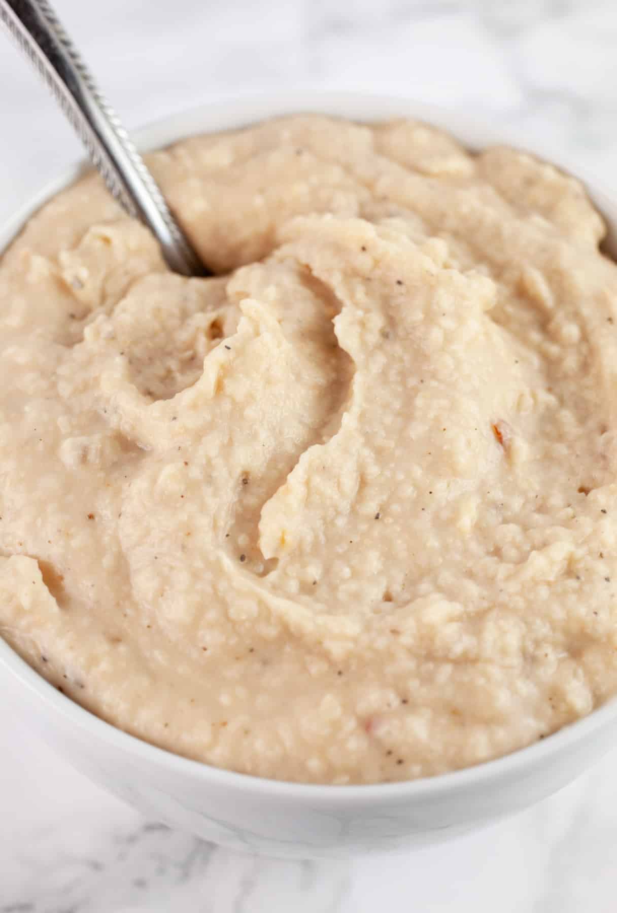 Cannellini bean dip in white bowl with spoon.