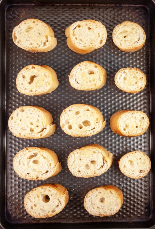 Untoasted baguette slices on baking sheet.