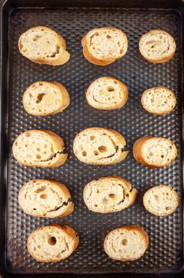 Toasted slices of baguette on baking sheet.