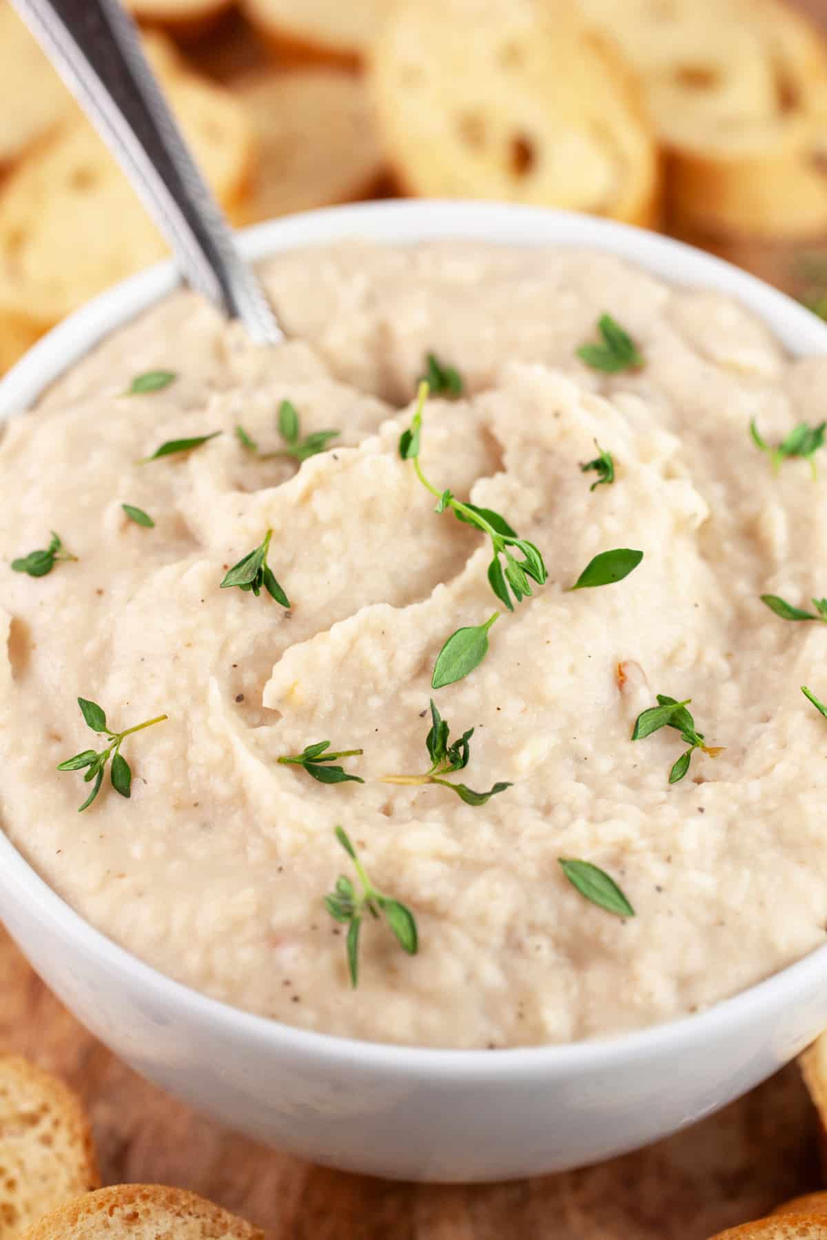 Cannellini bean dip in white bowl with toasted crostini.