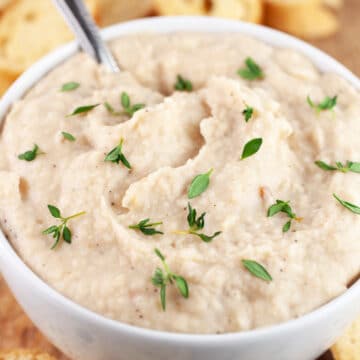 Italian white bean dip in white bowl garnished with fresh thyme.