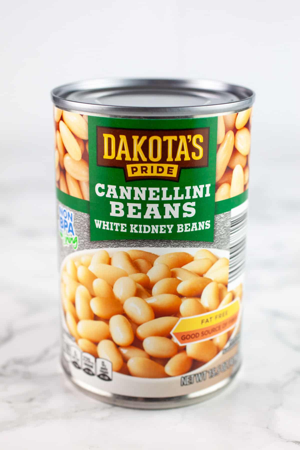 Unopened can of cannellini beans on white surface.